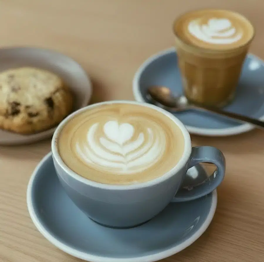 A flat white and cookie on the counter